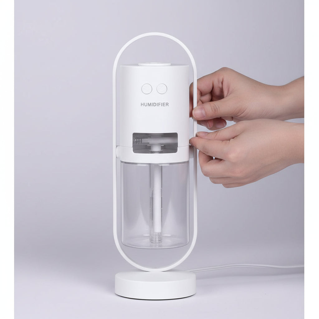 White handheld device with a transparent container, held by two hands against a light gray background.